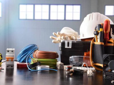 Composition with tools and electrical equipment on black table and industrial ship background. Horizontal composition. Front view.